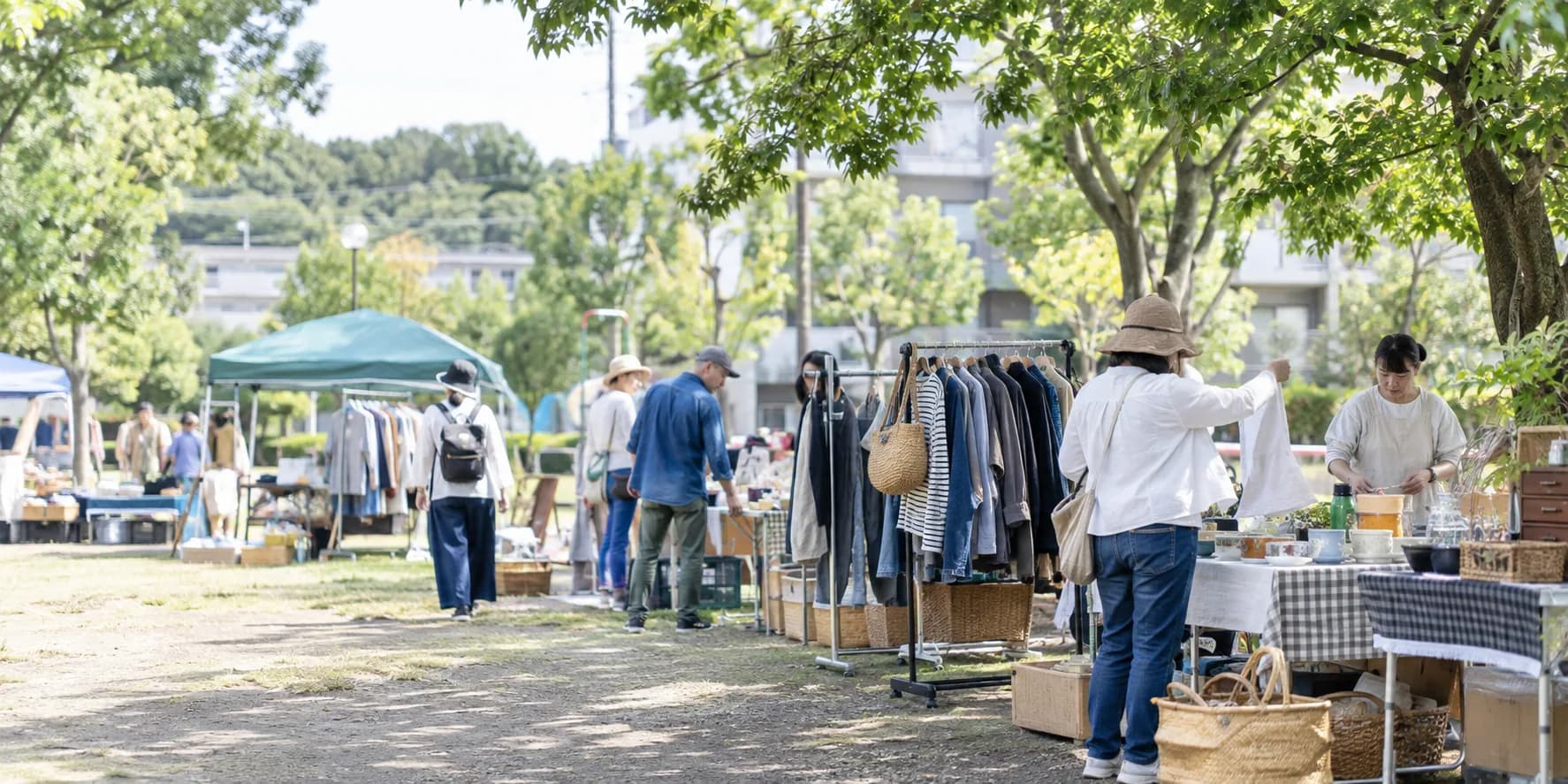 公園のフリーマーケット会場で衣類や日用品を見て回る人々